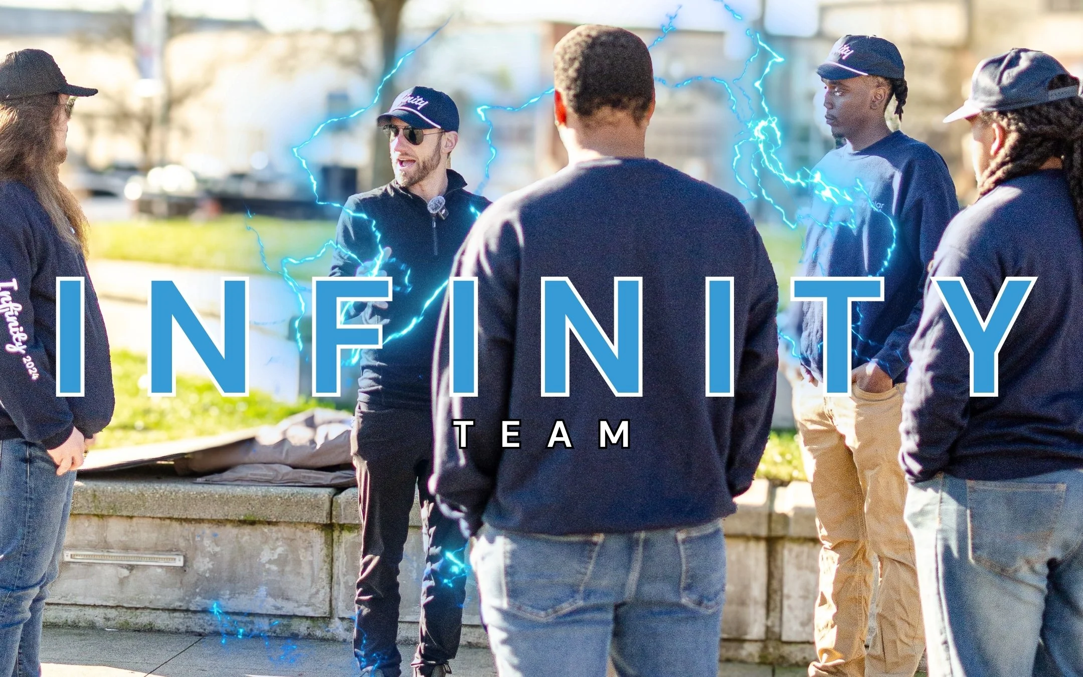 A group of people standing outdoors in a circle, having a conversation, with the word 'INFINITY' and 'TEAM' overlaid on the image, and blue lightning effects around the scene.