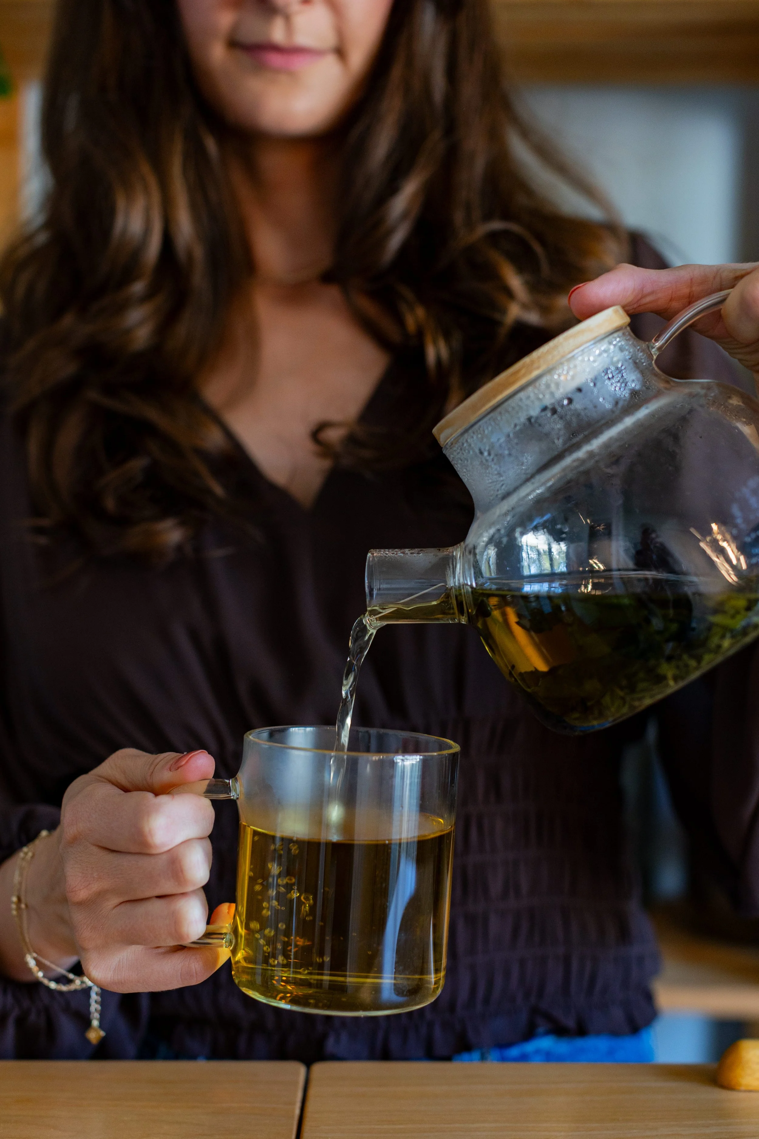 woman-pouring-a-cup-of-herbal-tea-into-a-glass-mug