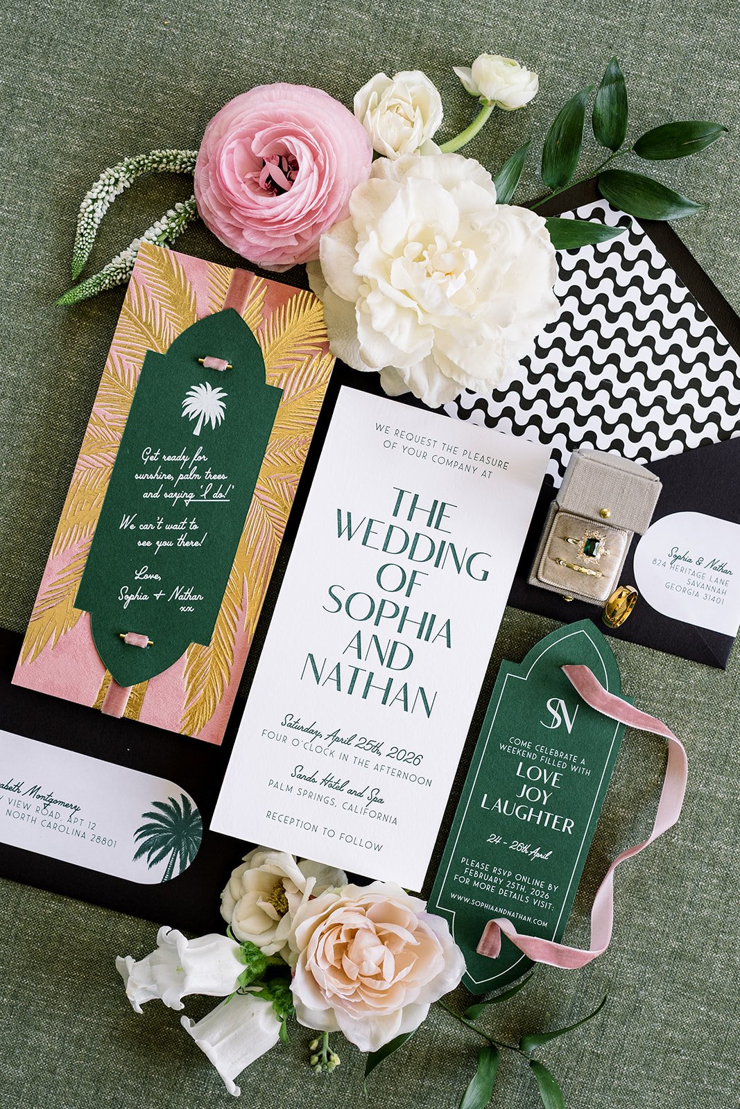 Wedding invitation suite with floral accents, including pink and white flowers, and green and pink tags with details about the wedding of Sophia and Nathan.