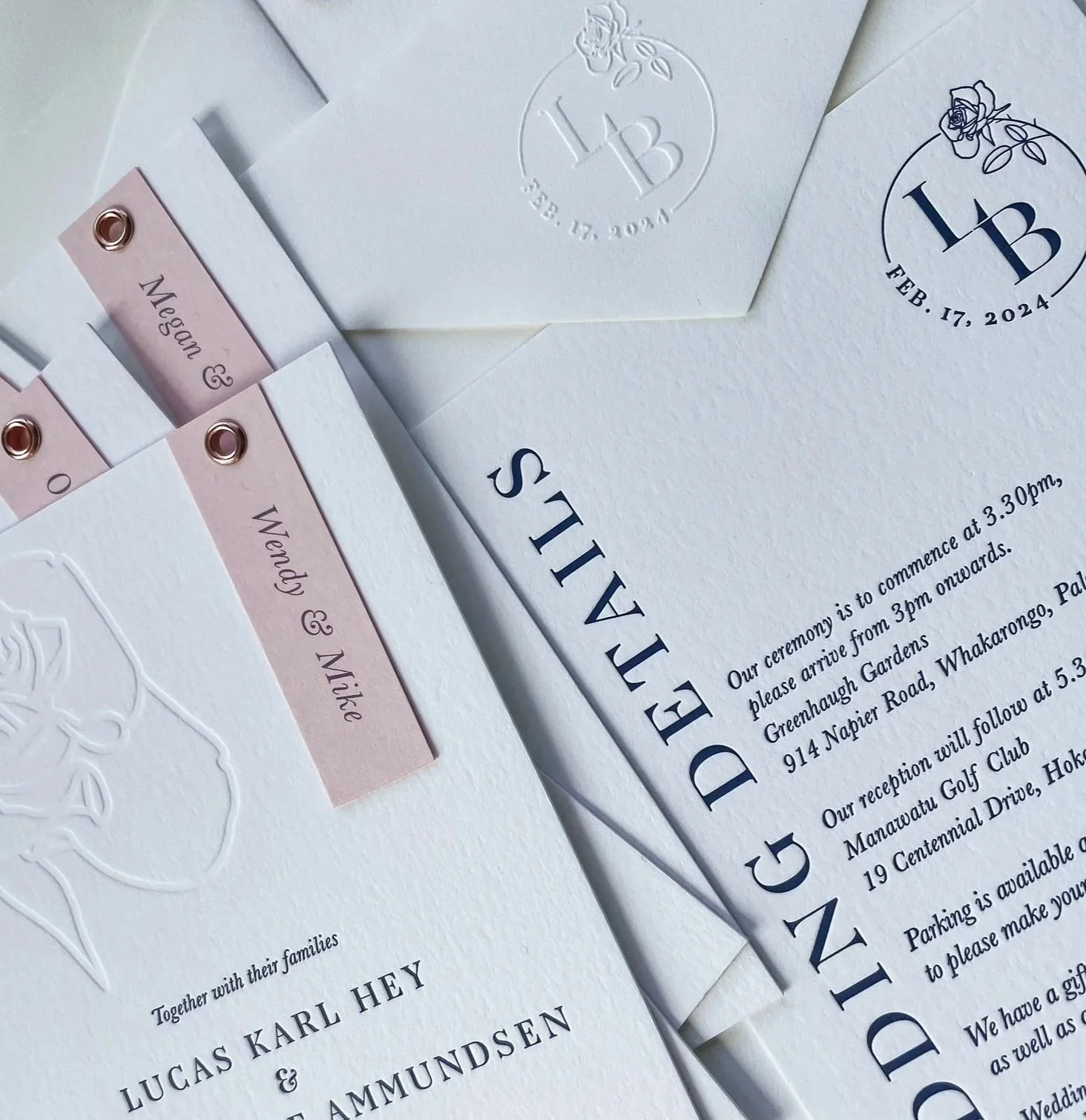 Wedding invitations and RSVP cards with elegant embossed and printed text, featuring a floral design and a soft pink accent for the RSVP card, all on textured white paper.