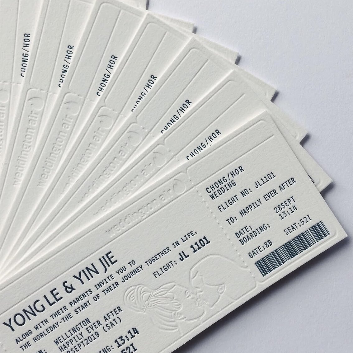 A stack of wedding invitation tickets for Yong Le and Yine, with embossed designs, flight details, and seating information.