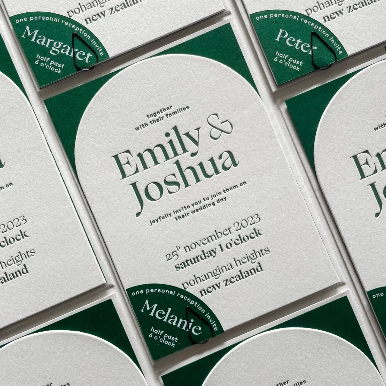 Wedding invitation card for Emily and Joshua with event details and RSVP card attached, featuring green and white design elements.