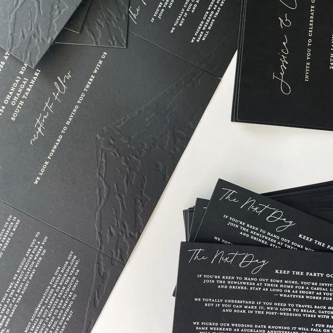 Wedding invitation cards with black and gray textured backgrounds featuring white elegant cursive and printed text.