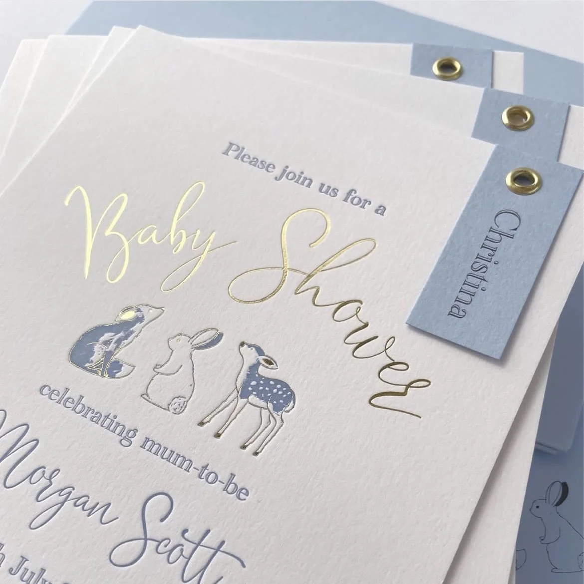 Invitation card for a baby shower with illustrations of three bunnies, celebrating a future mom named Megan Scott.