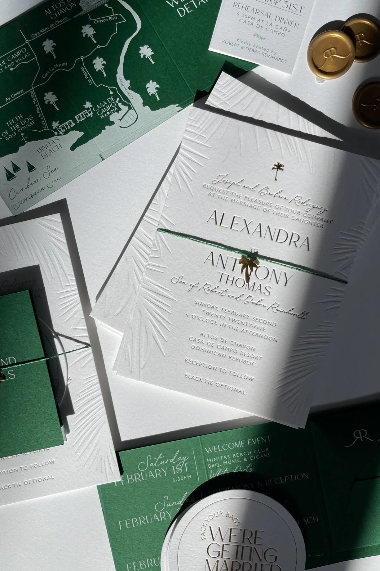 Wedding invitation cards and event details with an anniversary and wedding plan, featuring a green map of Casa de Campo Marina and white embossed stationery with gold palm tree embellishment, setting the scene for a wedding celebration.
