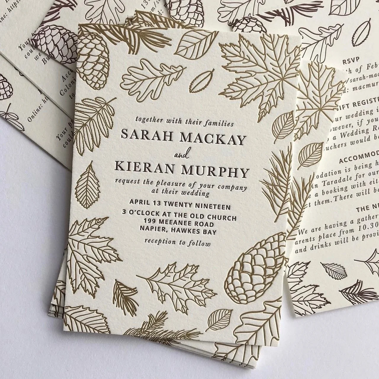 Wedding invitation featuring a cream-colored background with gold and black outline illustrations of leaves and pinecones. The text invites Sarah Mackay and Kieran Murphy to their wedding celebration, mentioning the date, time, venue, and RSVP details.
