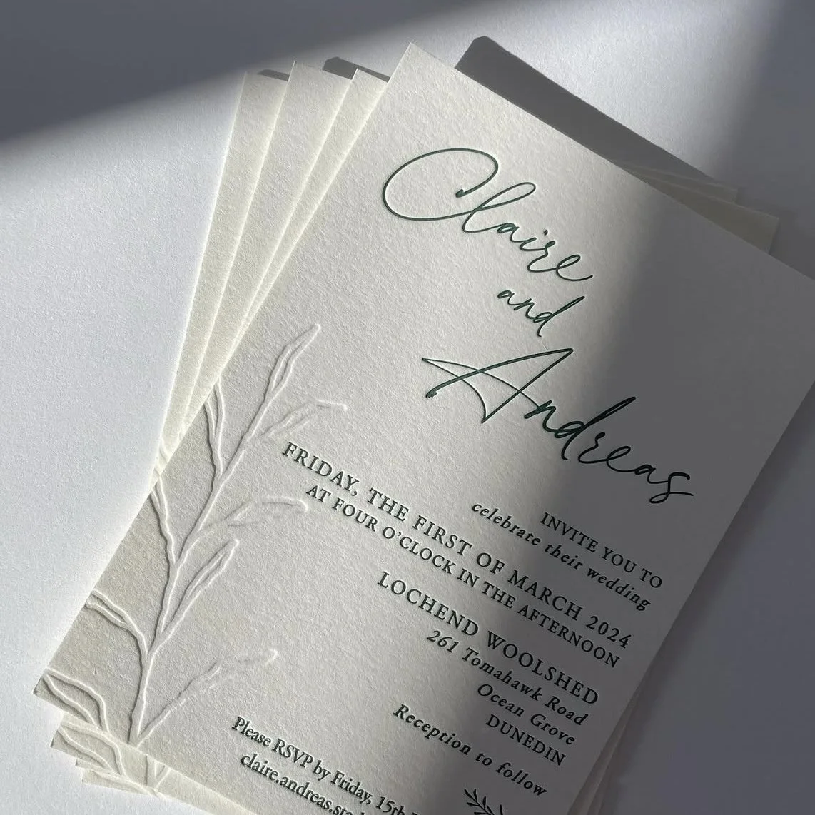 Wedding invitation card for Claire and Andreas with details of the date, time, location, and RSVP request on textured paper.