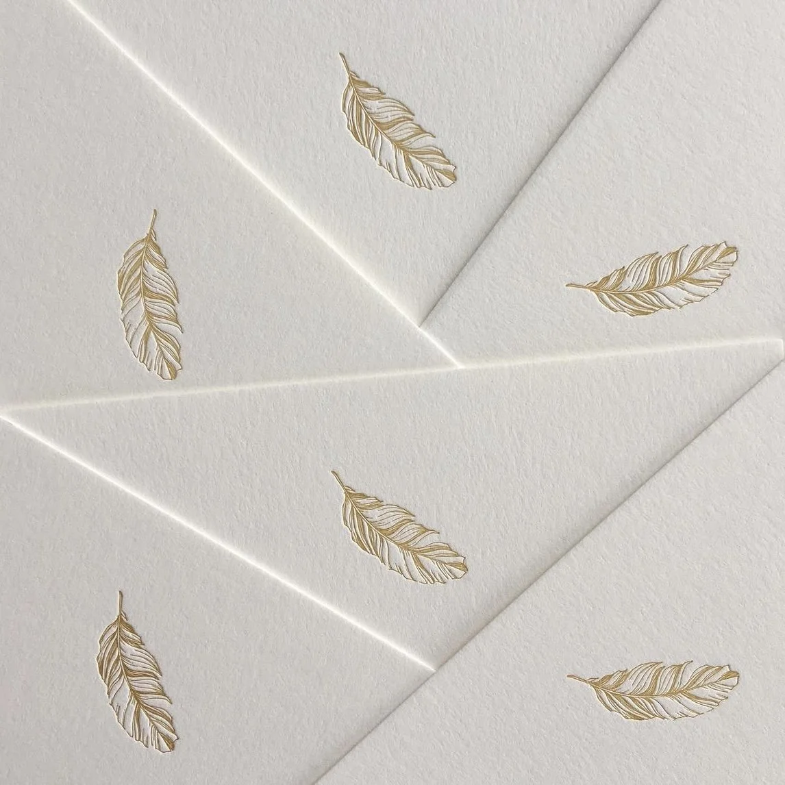 Cream-colored stationery with gold foil feather designs.
