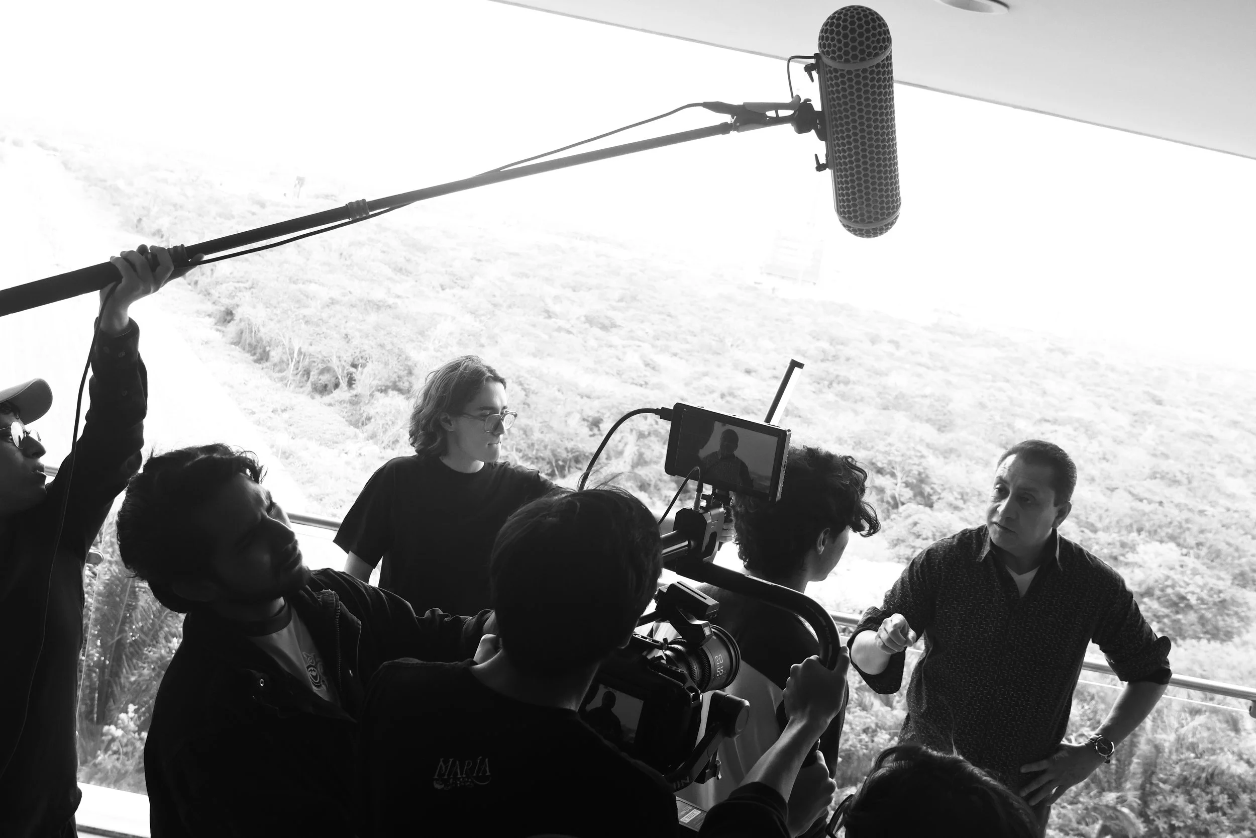 Un equipo de filmación grabando a un hombre que parece estar dando una entrevista, con una vista panorámica de la naturaleza al fondo.