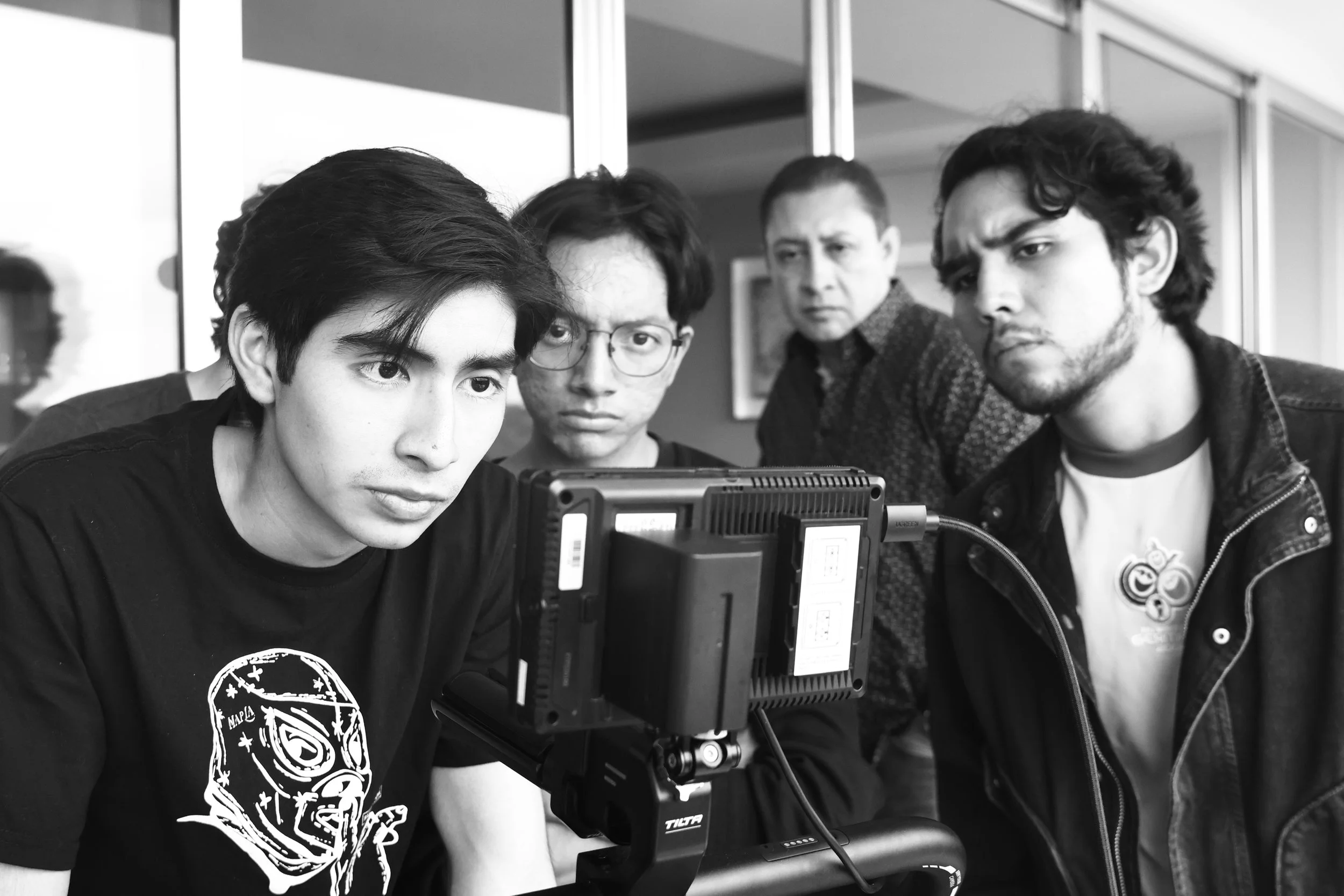 Cuatro personas observando una pantalla de una cámara en un entorno de interior.