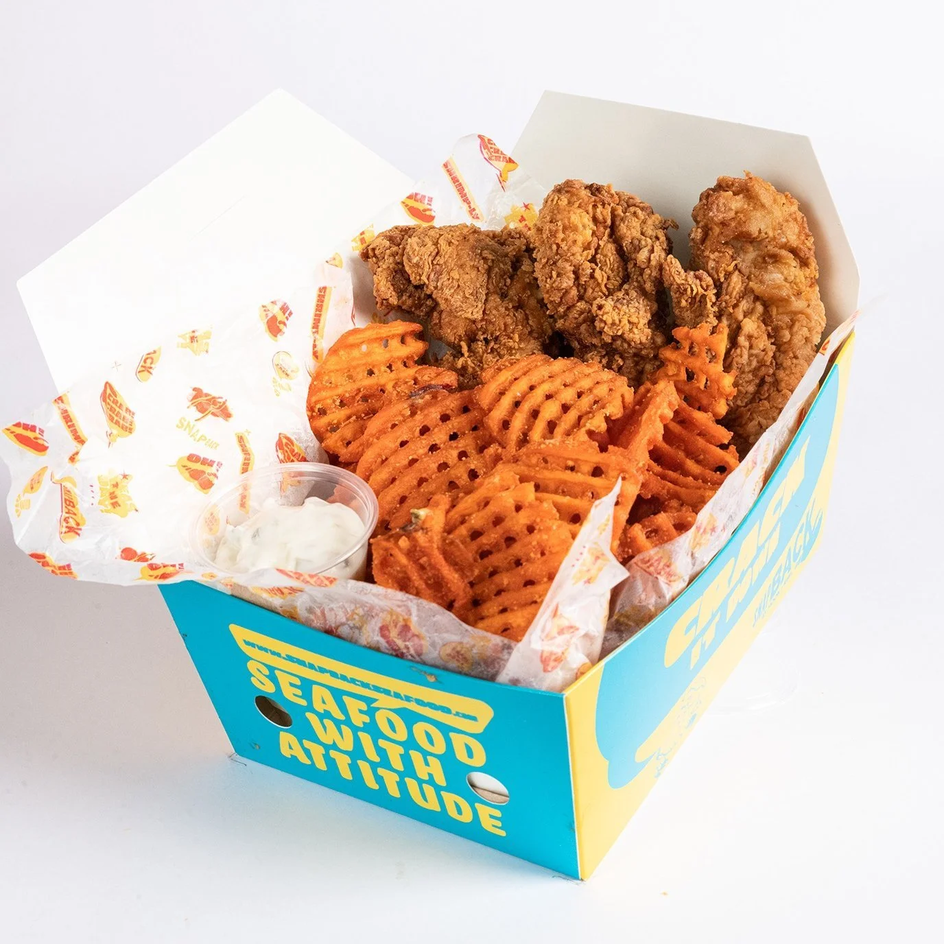 A box of fried chicken tenders, waffle fries with seasoning, a small cup of ranch dipping sauce, and a side of waffle-cut sweet potato fries.
