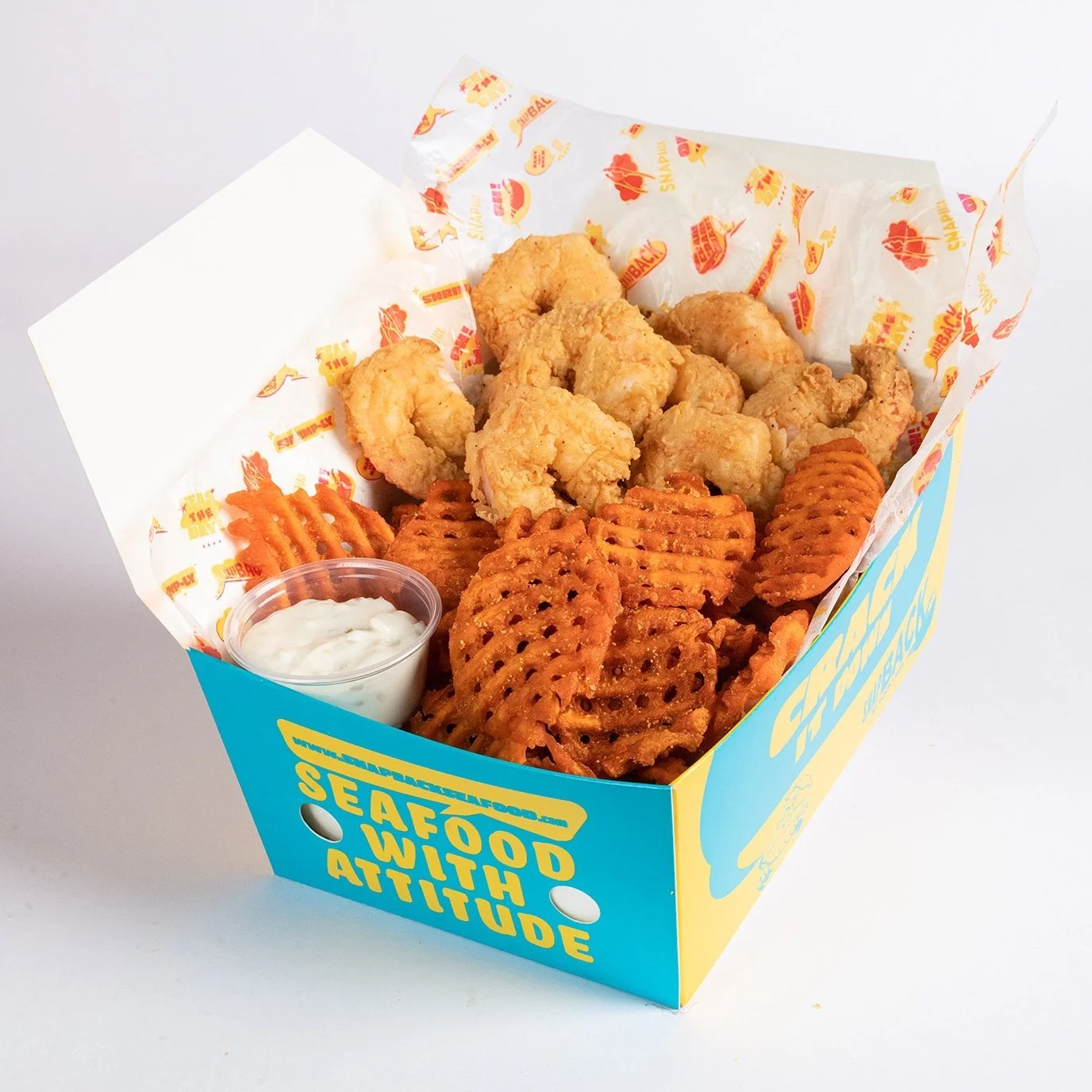Fried chicken tenders, waffle fries, sweet potato waffle fries, and a small container of dipping sauce inside a blue and yellow box with the slogan 'SEAFOOD WITH AN ATTITUDE'.