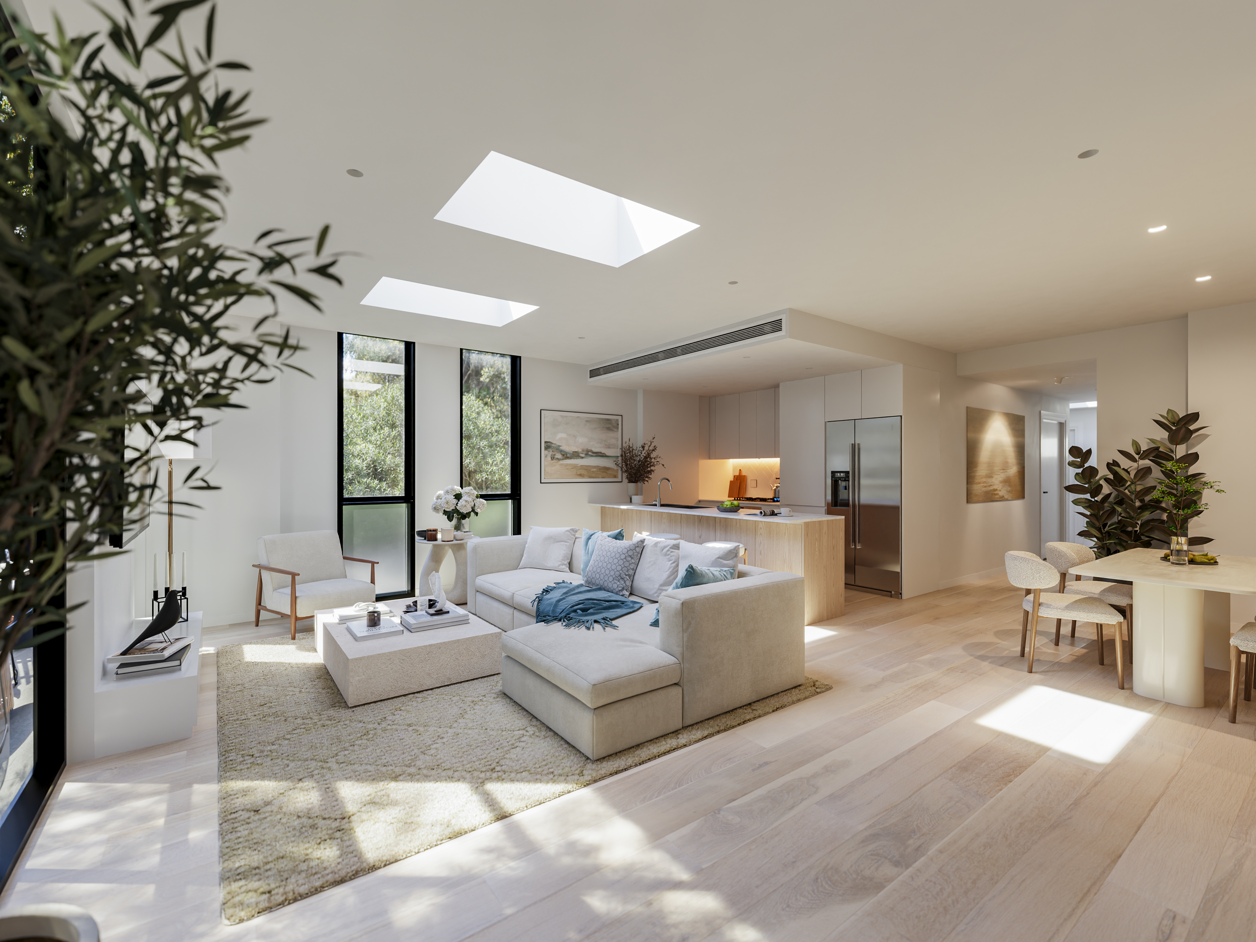 Modern open-concept living room and kitchen with natural light, white walls, light wooden flooring, a cream sectional sofa, a neutral area rug, large windows, and minimalistic decor.