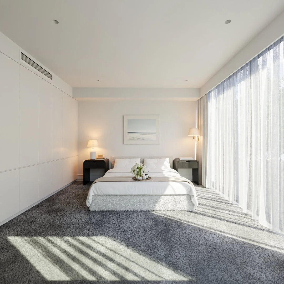 Bright bedroom with white walls, large window with sheer curtains, bed with white linens, two bedside tables with lamps, framed art on the wall, and gray carpet.