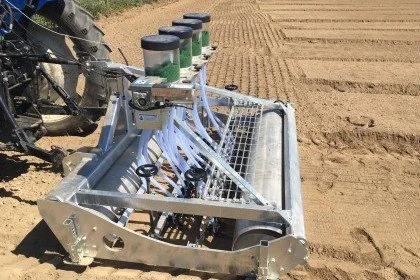 Agricultural seed planter machine on a plowed field.
