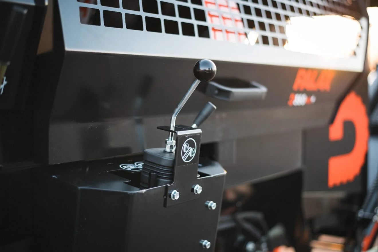 Close-up of a black and silver engine control lever attached to a piece of heavy machinery.