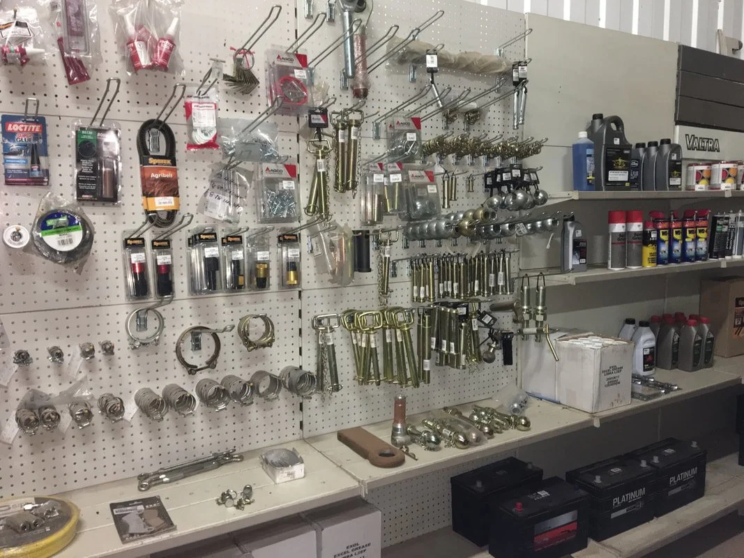 Shop wall with various hardware tools and supplies, including wrenches, bolts, screws, lubricants, and small storage boxes.