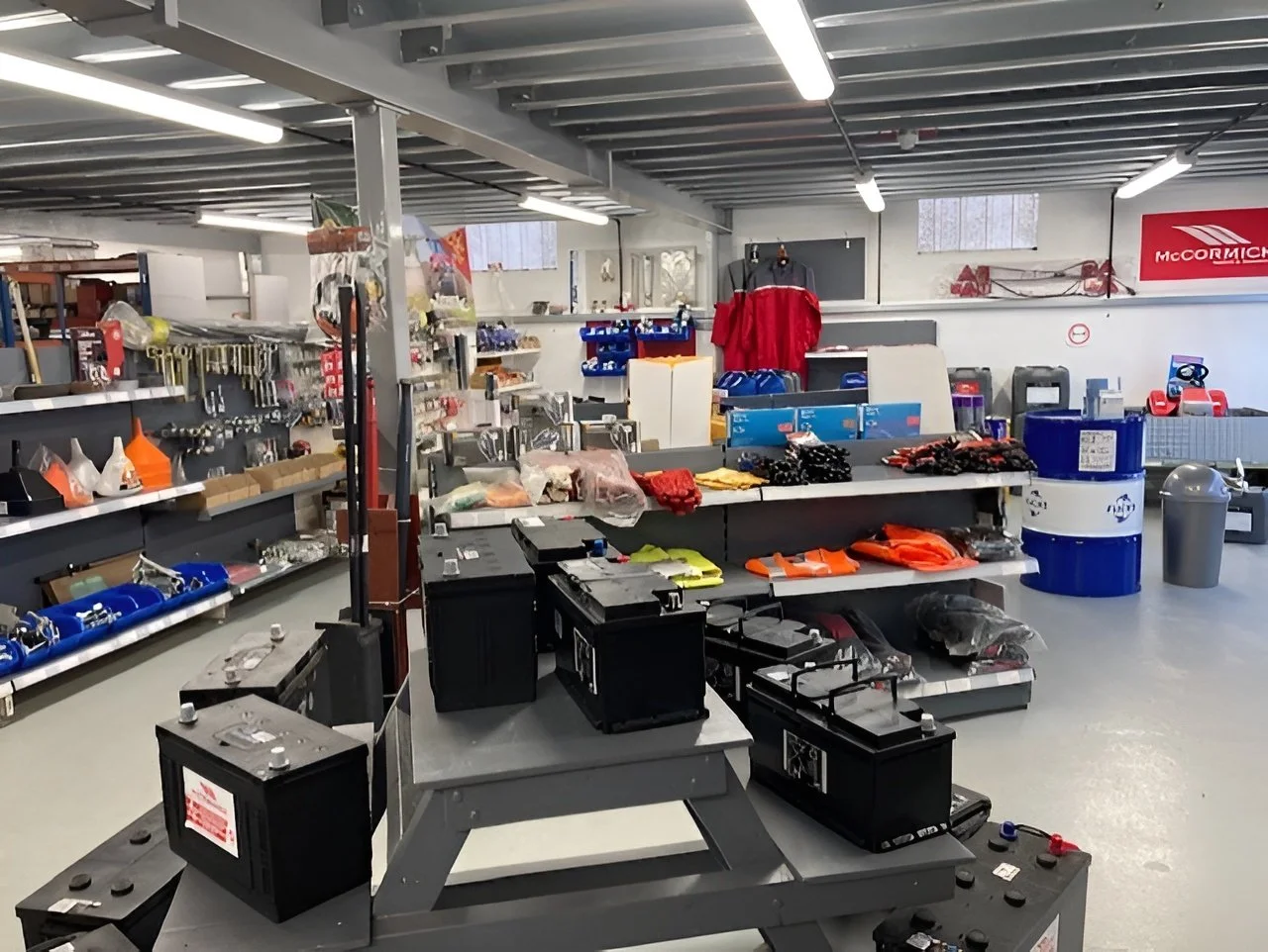 Interior of a hardware store with tools, clothes, and supplies on shelves and tables.