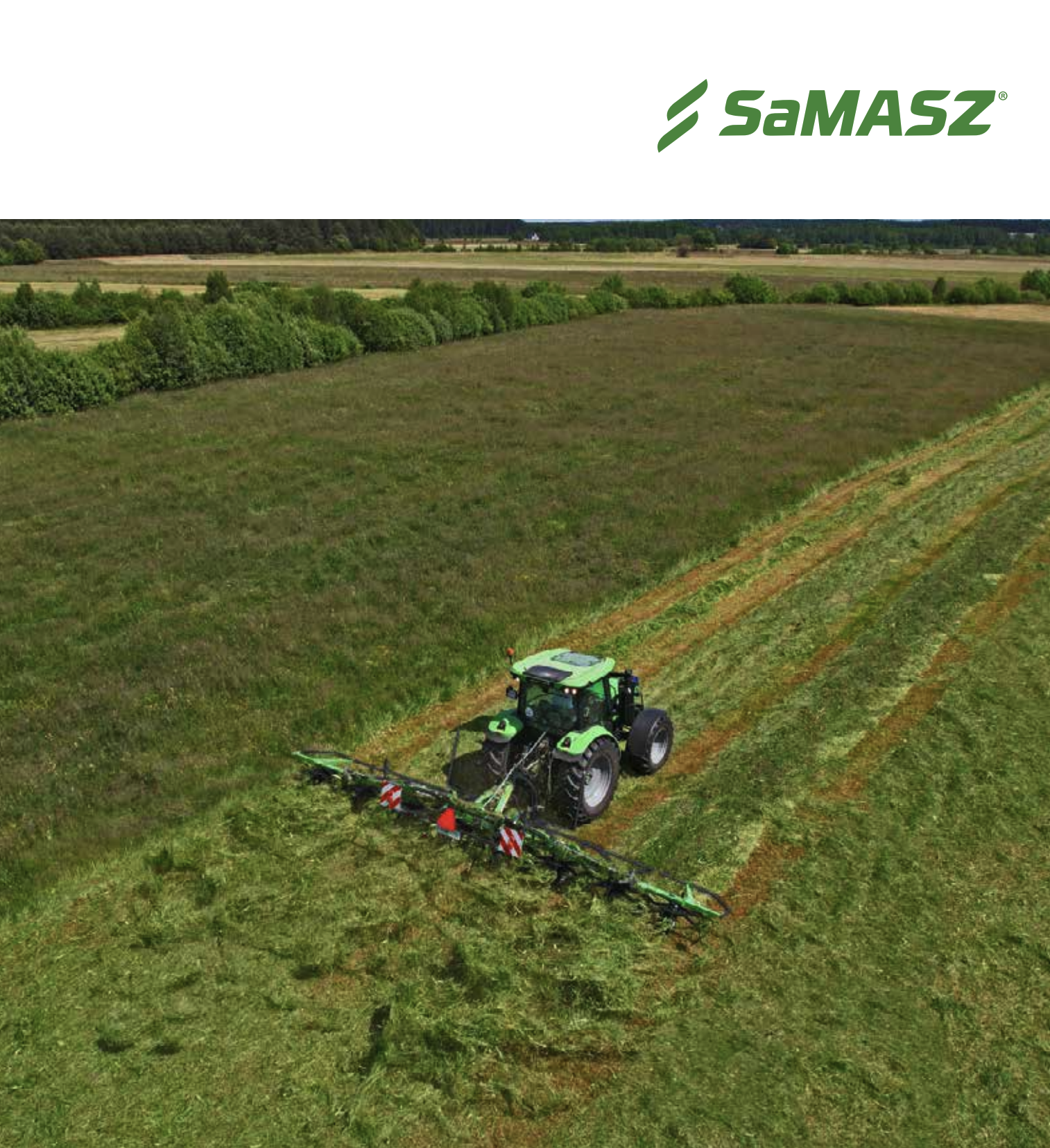 A green tractor with a mower attached is cutting grass in a large field surrounded by trees in the distance.