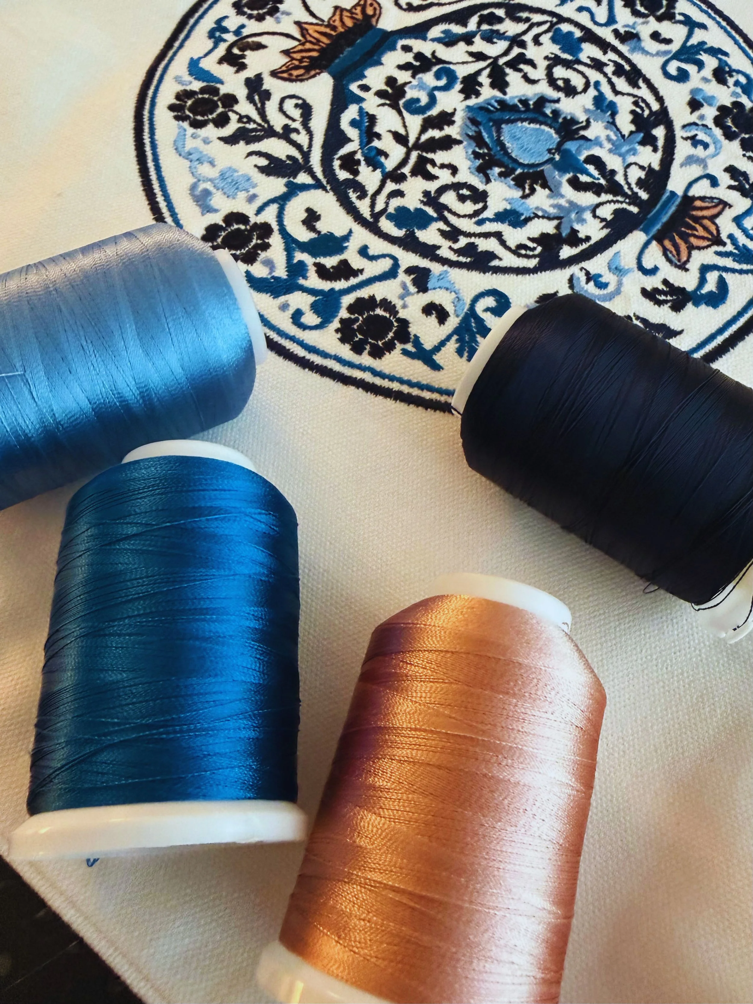 Close-up of Blu Pietra embroidery threads in blue and terracotta on natural cotton