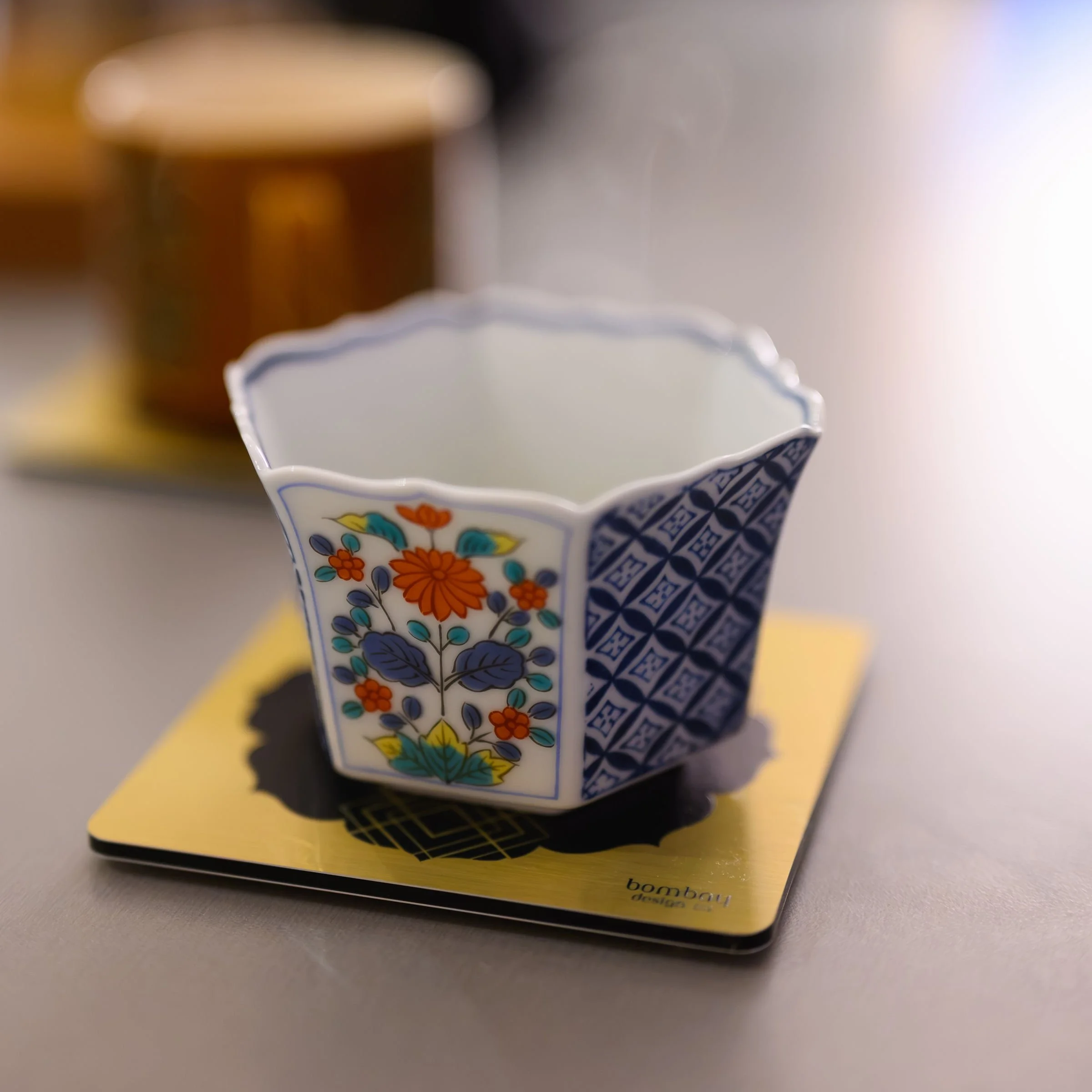 A hand painted Japanese tea cup placed on a Bombay Deco Coaster