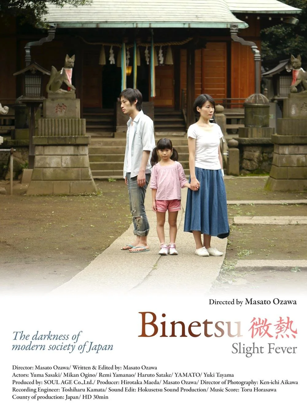 神社の前で手をつないでいる家族の写真。若い男性、女性、子供の三人。