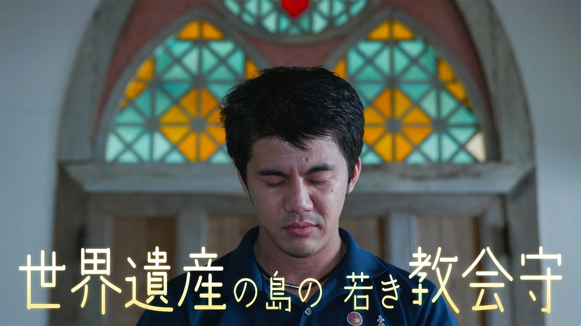 教会のステンドグラスの前で目を閉じている男性。