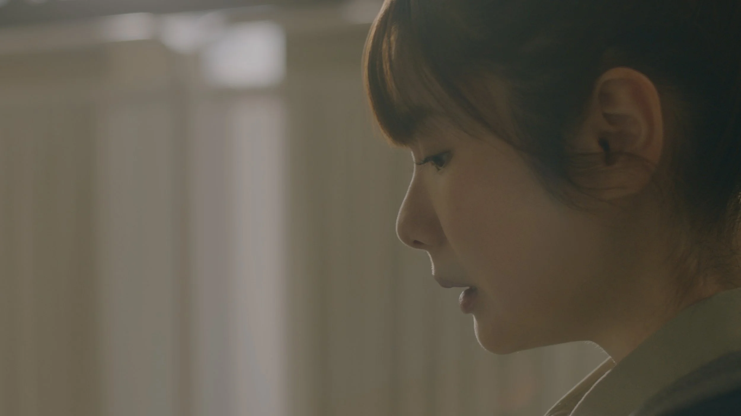 女性の横顔のクローズアップ写真、穏やかな表情、背景はぼやけている。