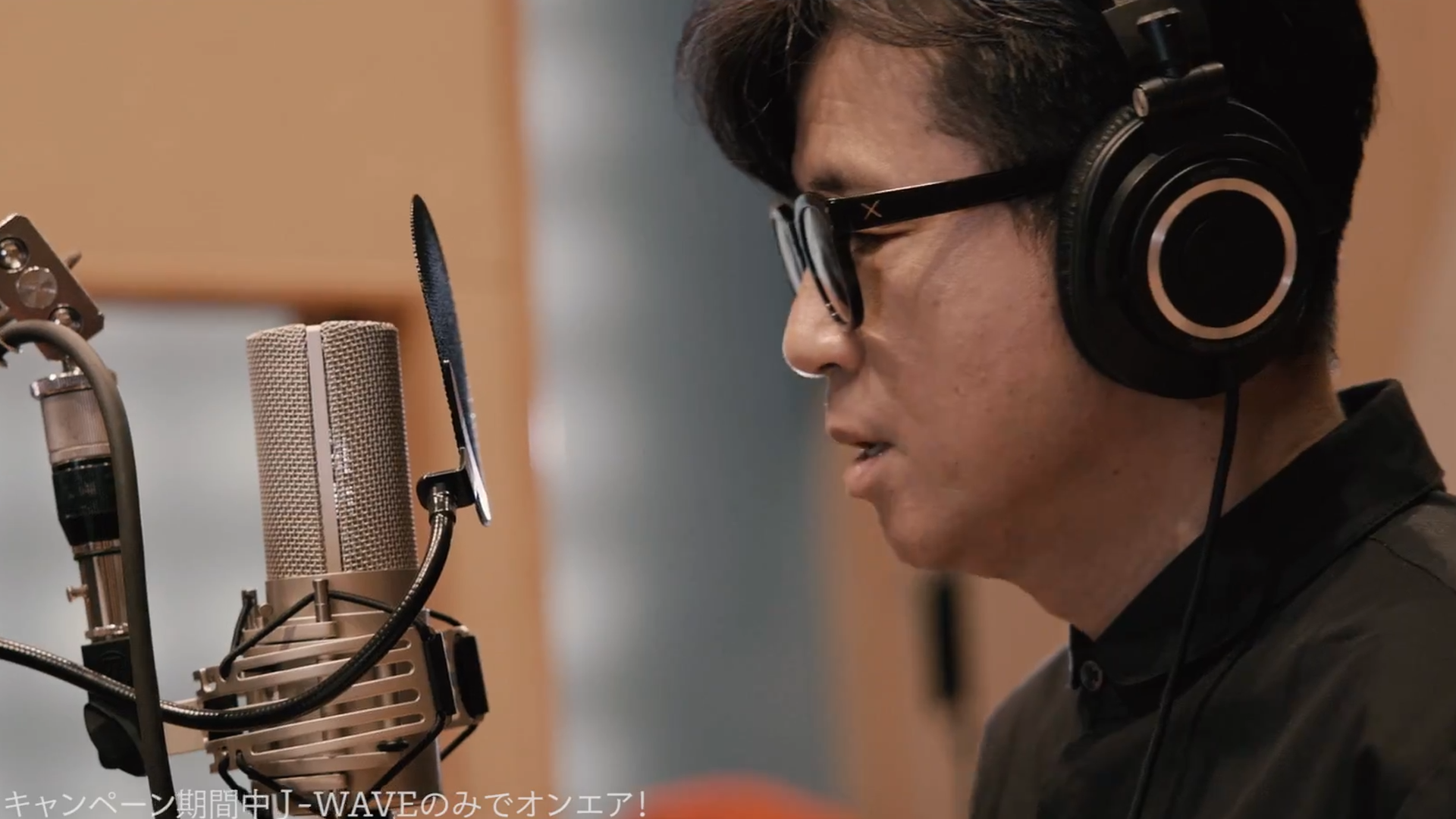 男性がヘッドフォンをつけてスタジオで録音している様子