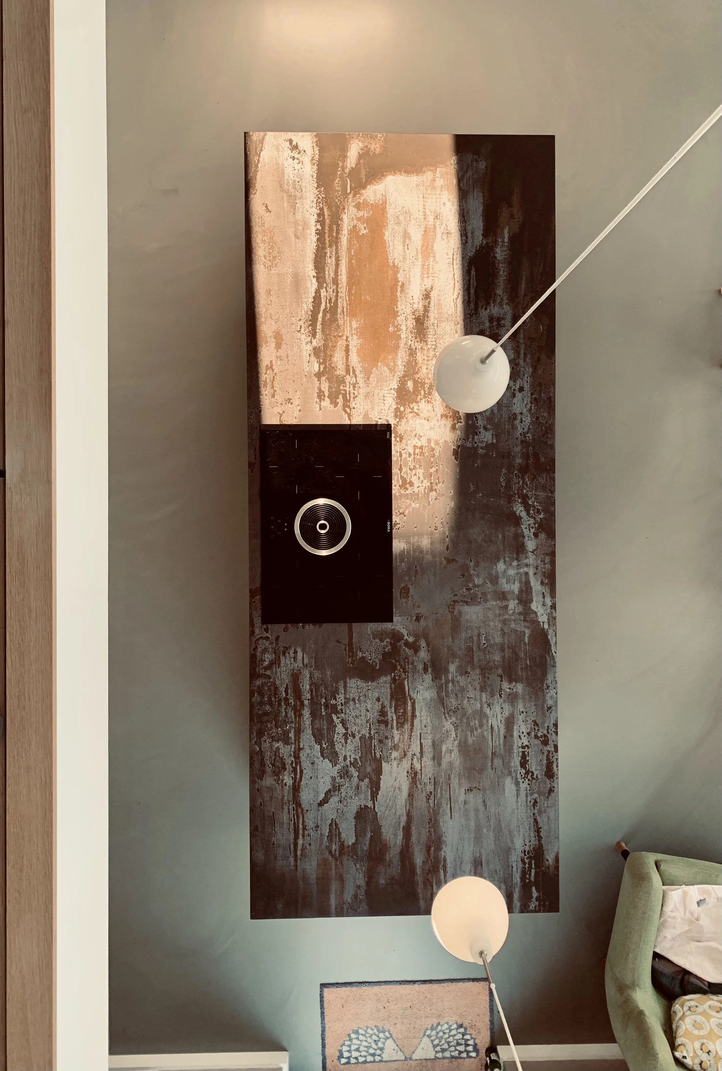 A ceiling view showing a textured metallic surface, a black speaker, two hanging pendant lights, and part of a green armchair.