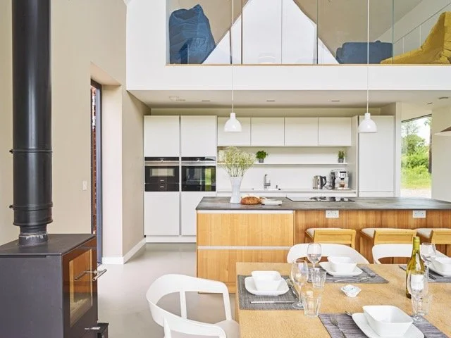 Modern kitchen with white cabinets, wooden island, and dining table set with glasses and plates