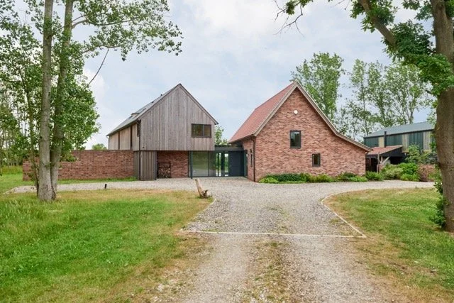 A  Grand Design luxury holiday home surrounded by trees with a gravel driveway leading up to them.