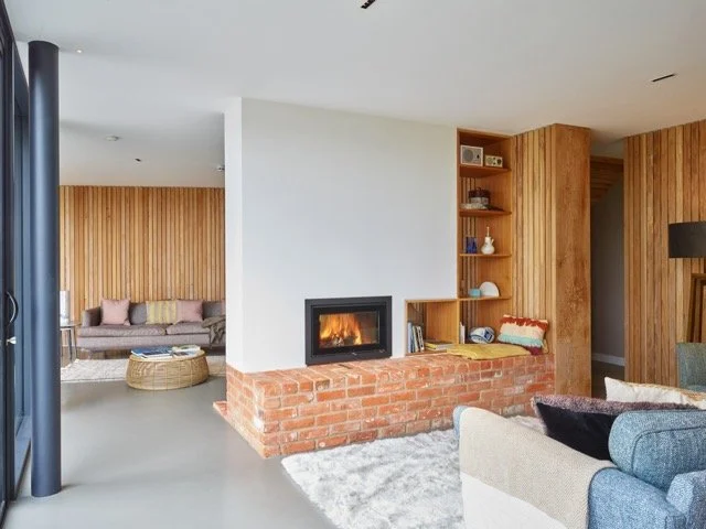 Living room with a brick fireplace, wooden wall paneling, and a cozy seating area.