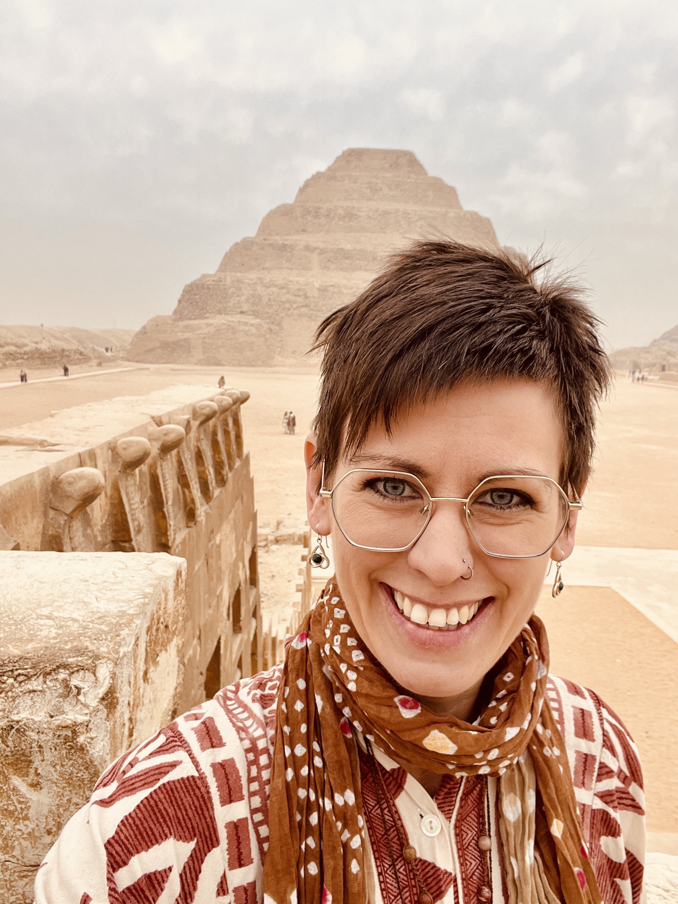 The Peoples Druid Charlie Bigwood smiling in front of the Saqqara step pyramid and cobra wall in Egypt.