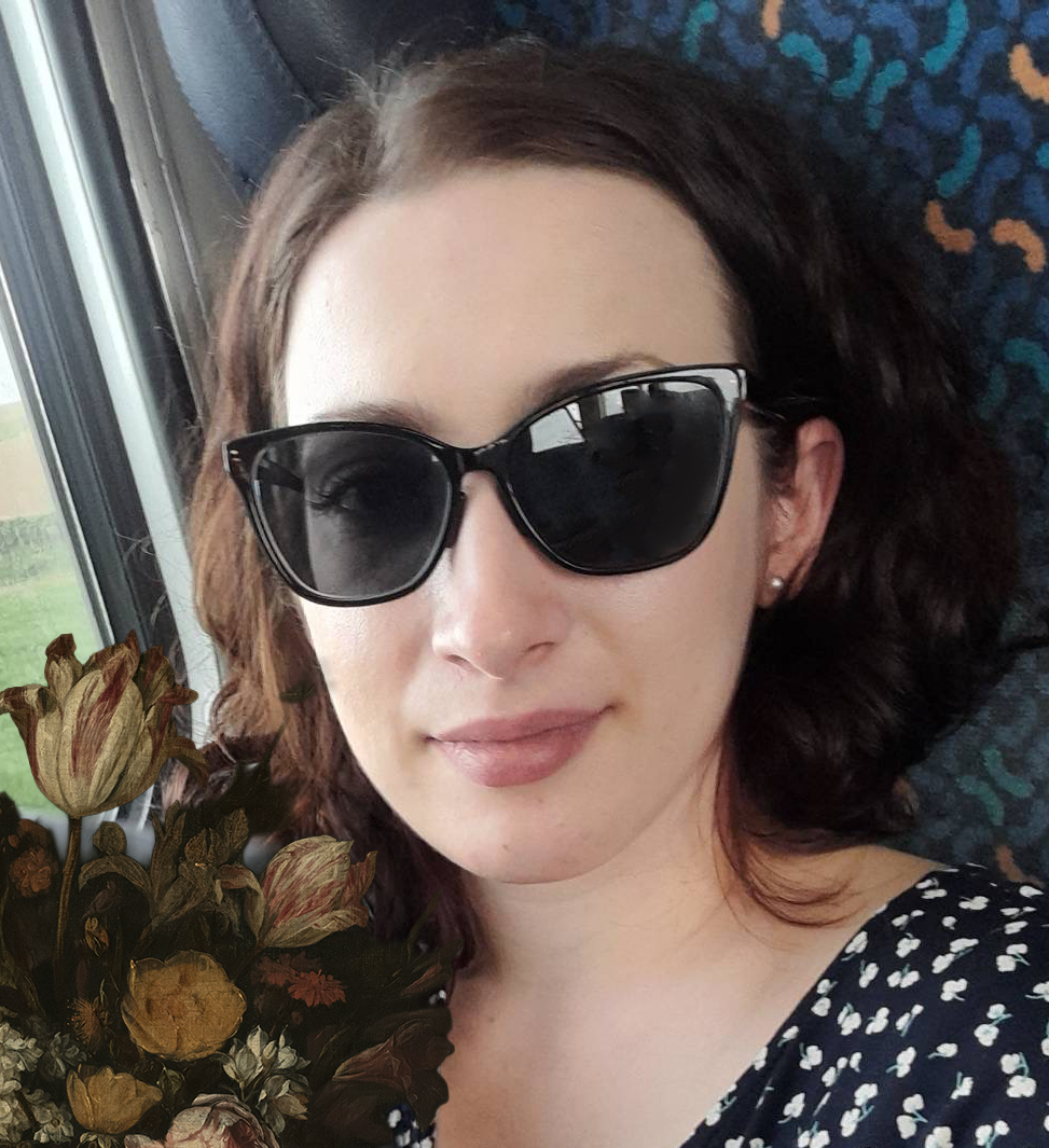A woman with light skin and dark wavy hair lying on a bus seat near a window, wearing black sunglasses and a patterned black and white top, with dried flowers overlaid in the bottom left corner.