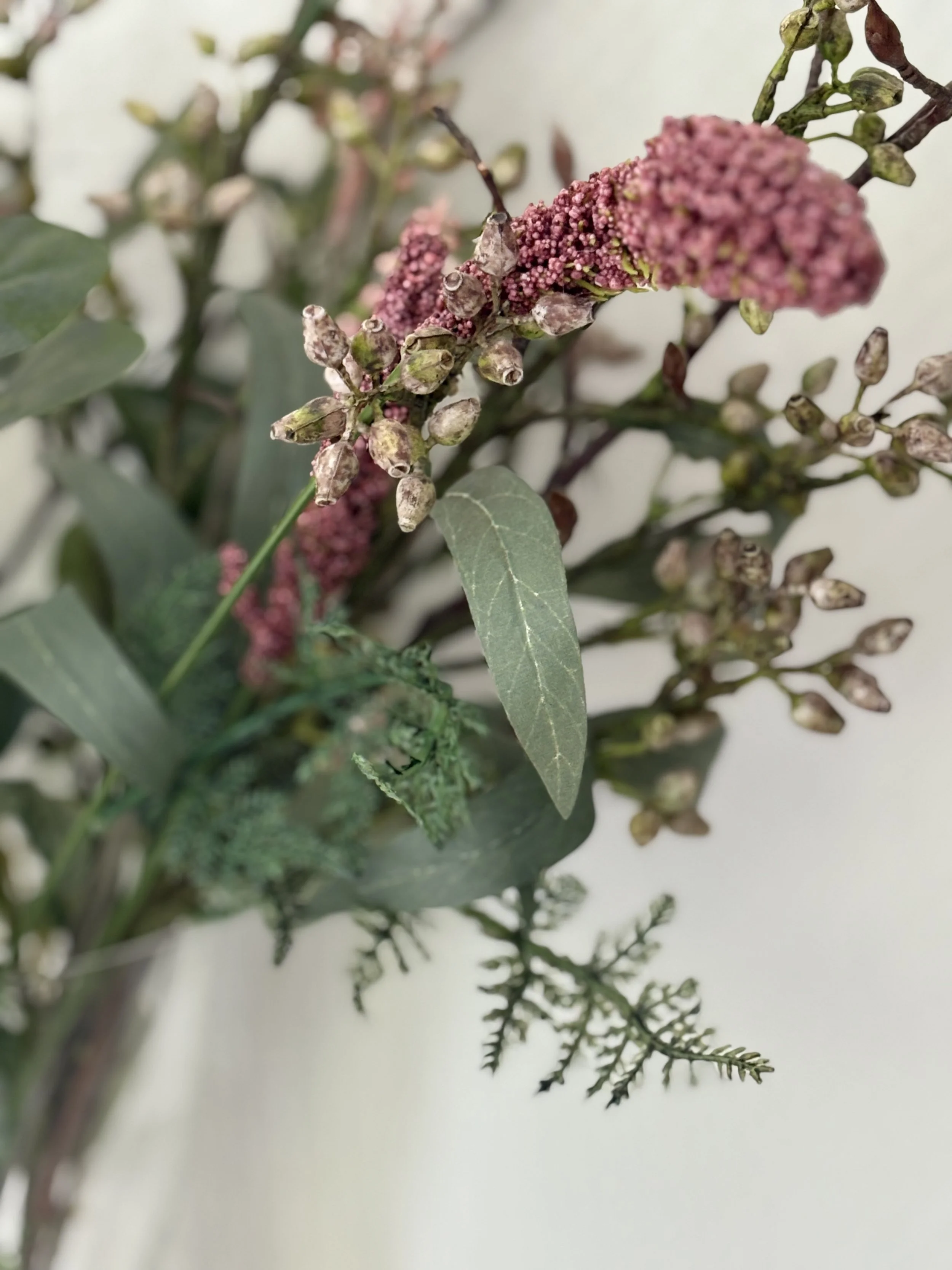 Nahaufnahme eines Straußes blühender und welker Blumen und Blätter.