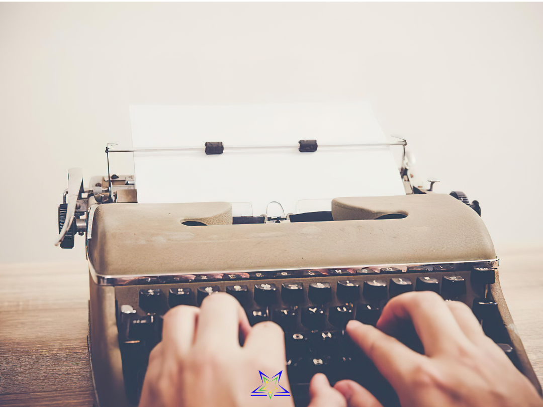 Image shows an old fashioned type writer loaded with a piece of paper. Hands are visible in the foreground, typing