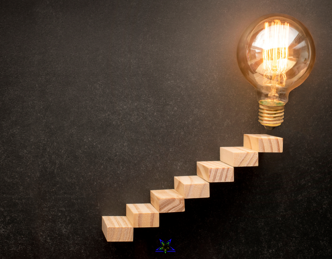 Image shows a staircase of wooden blocks against a dark background. There is an illuminated lightbulb at the top of the staircase