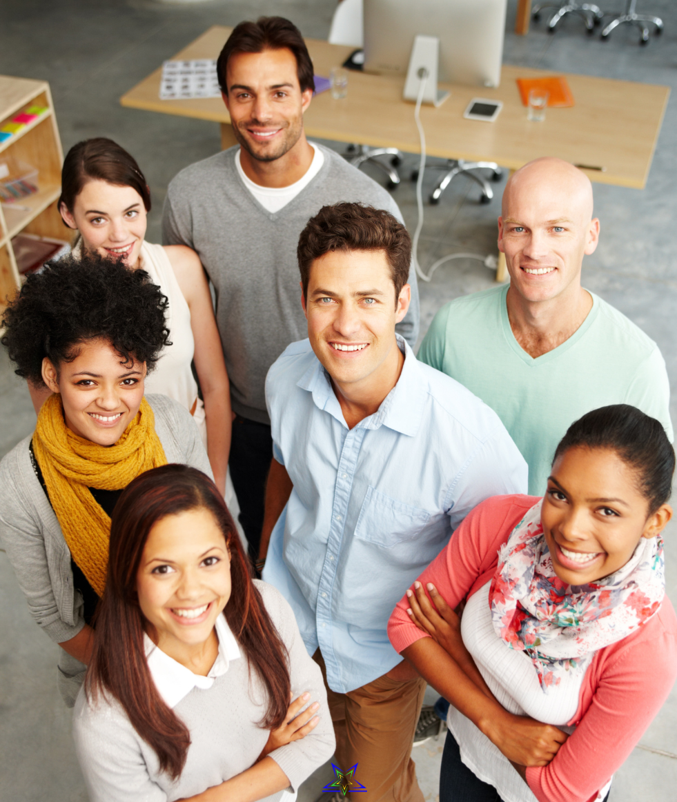 Image shows seven new leaders standing in a group in an office environment. They are all looking up at the camera and smiling