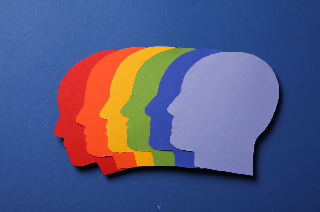 Image shows six overlapping brightly colour silhouettes of heads against a blue background. The heads are red, orange, yellow, green, blue and purple - each one is a single colour so together they produce a rainbow effect