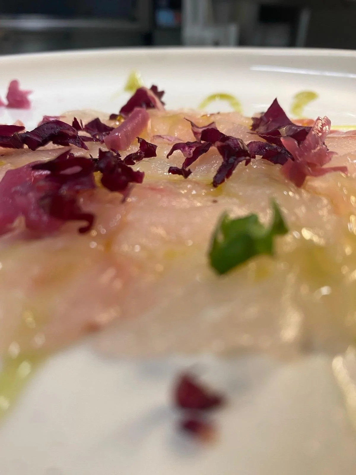 Piatto di carpaccio di carne guarnito con crostini di pane, rucola e scaglie di parmigiano.