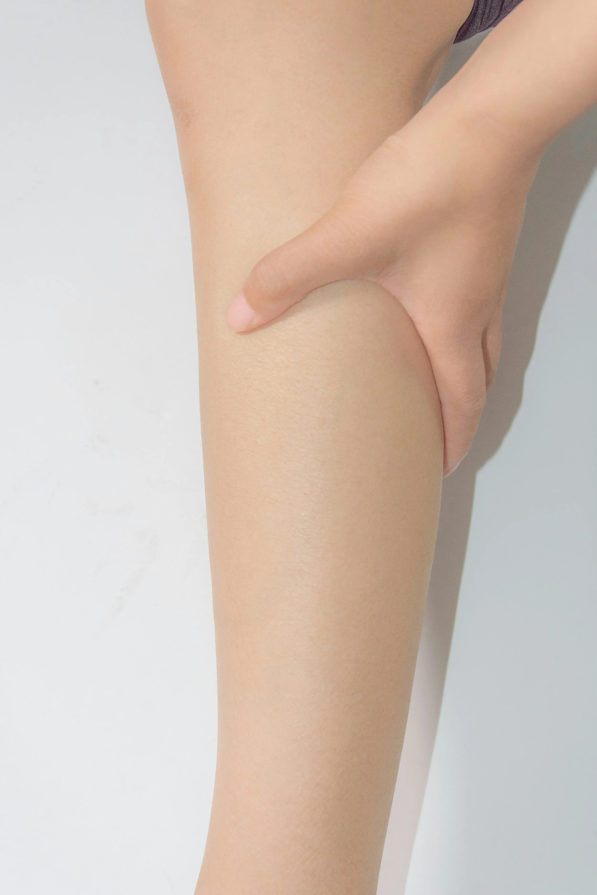 A close-up of a person's hand resting on their thigh against a plain white background.