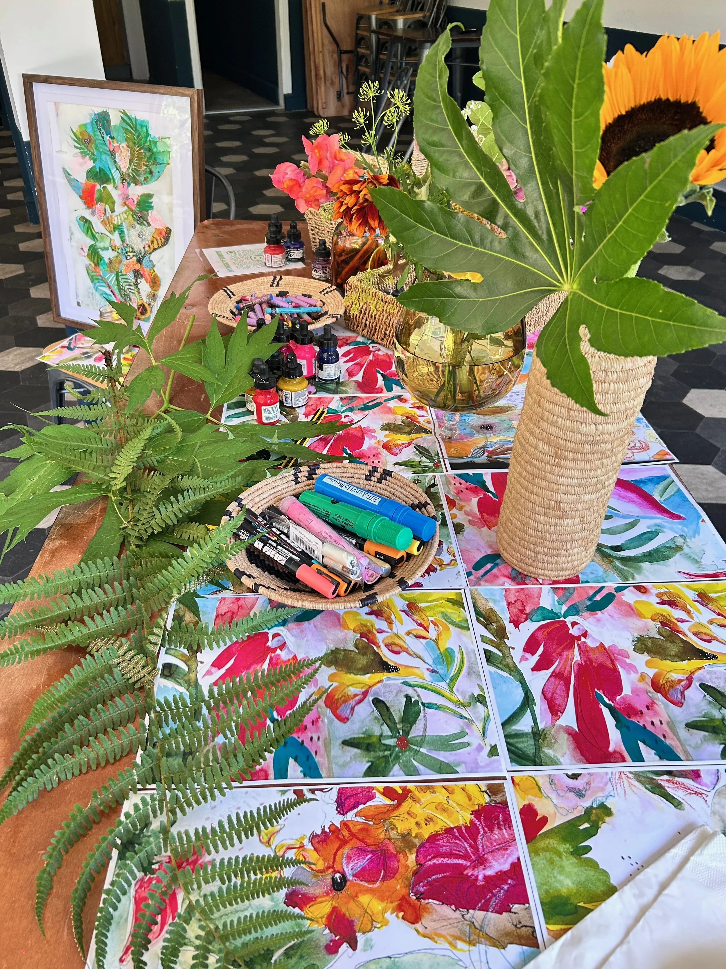 Table full of floral artwork, foliage and art materials during a Pause 7 Bloom workshop.