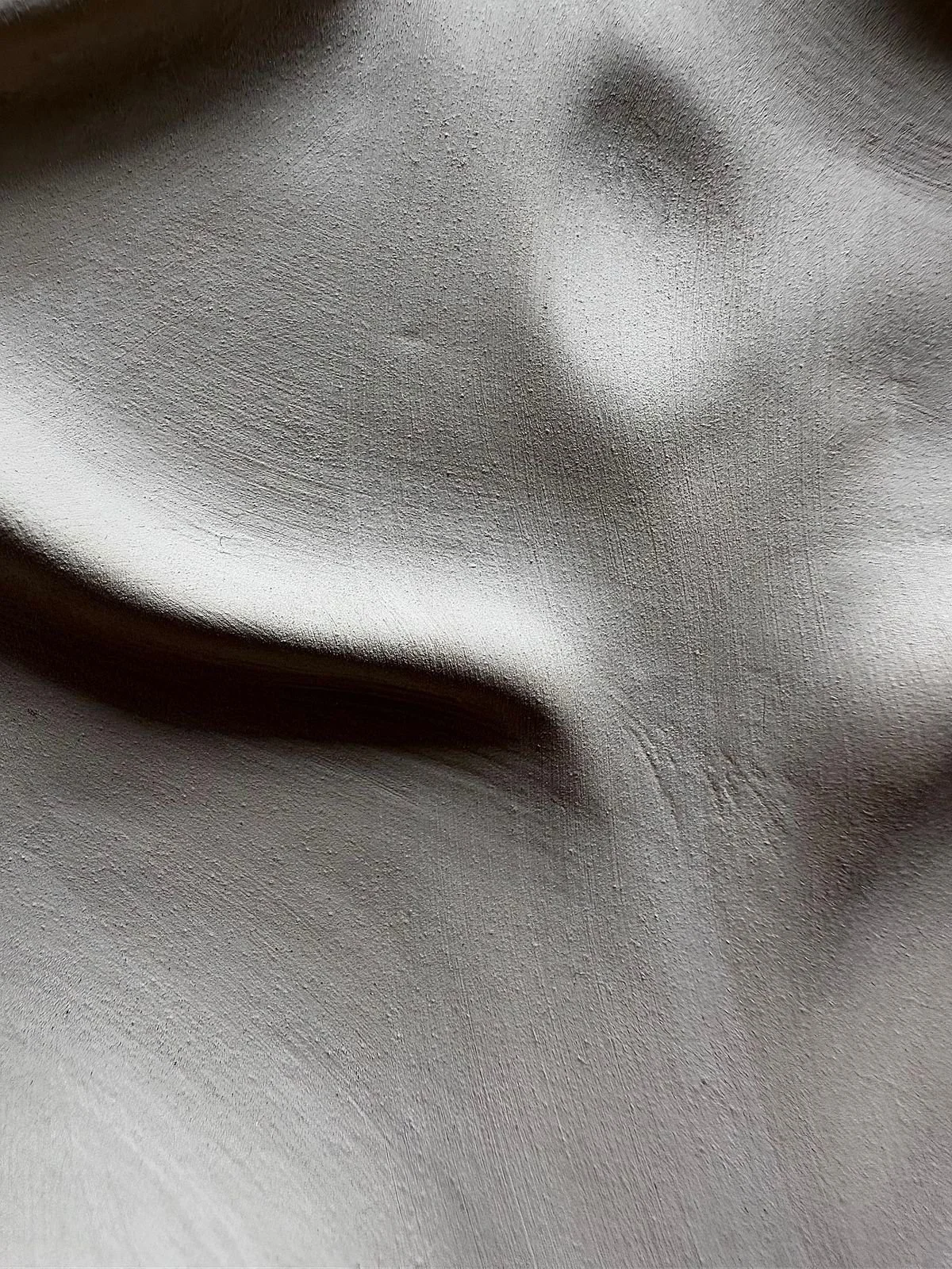 Close-up of a silver-colored statue or sculpture of a human face with closed eyes, showing detailed facial features.