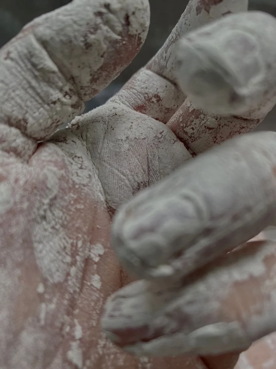 Close-up of a person's fingers covered in white and dusty construction or drywall compound.
