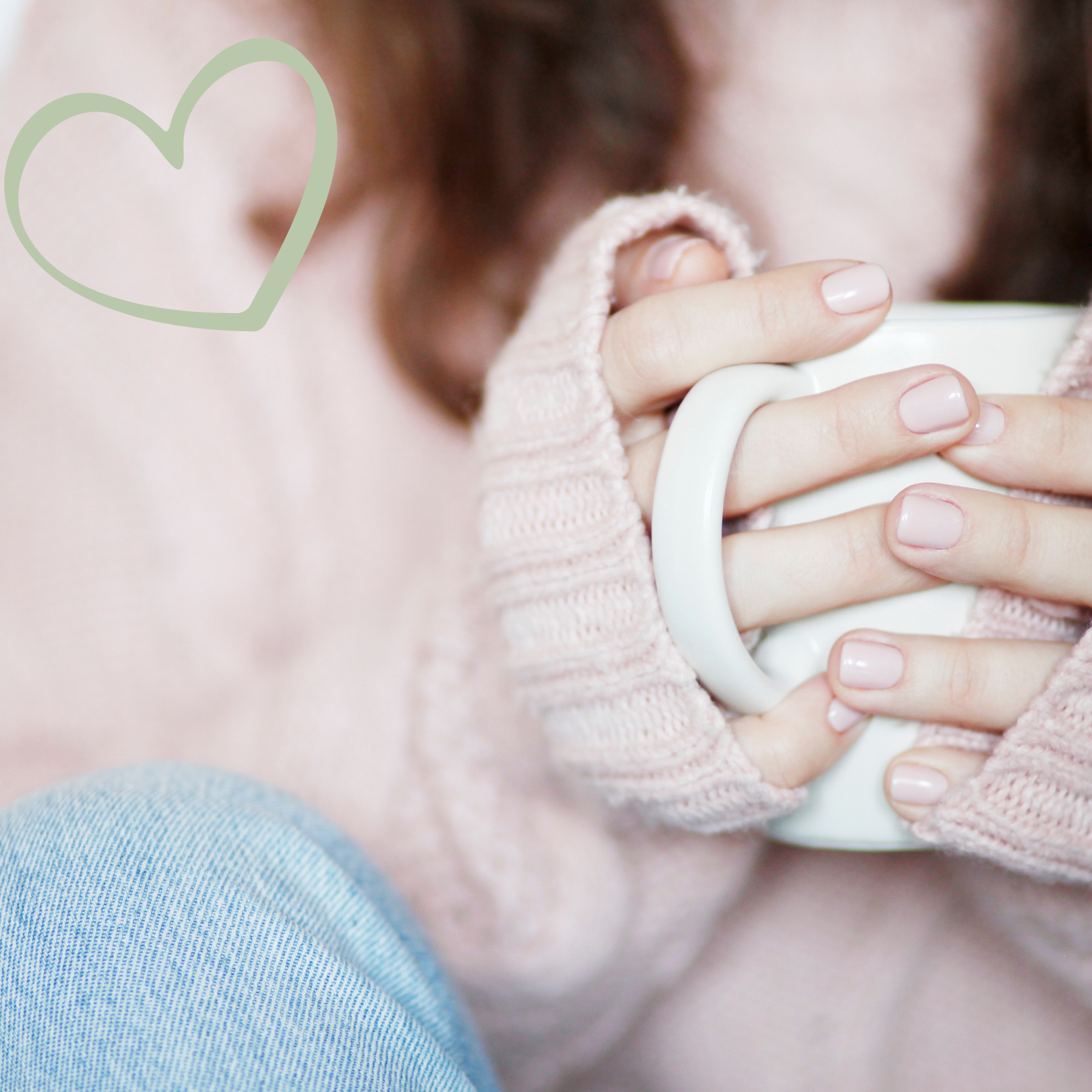 Person wearing pink sweater holding a white mug with both hands, with a heart outline in the top left corner.
