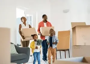 Une famille déménage avec des cartons dans un salon lumineux.