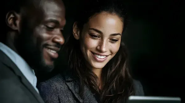 Un homme et une femme regardant un écran, souriant.