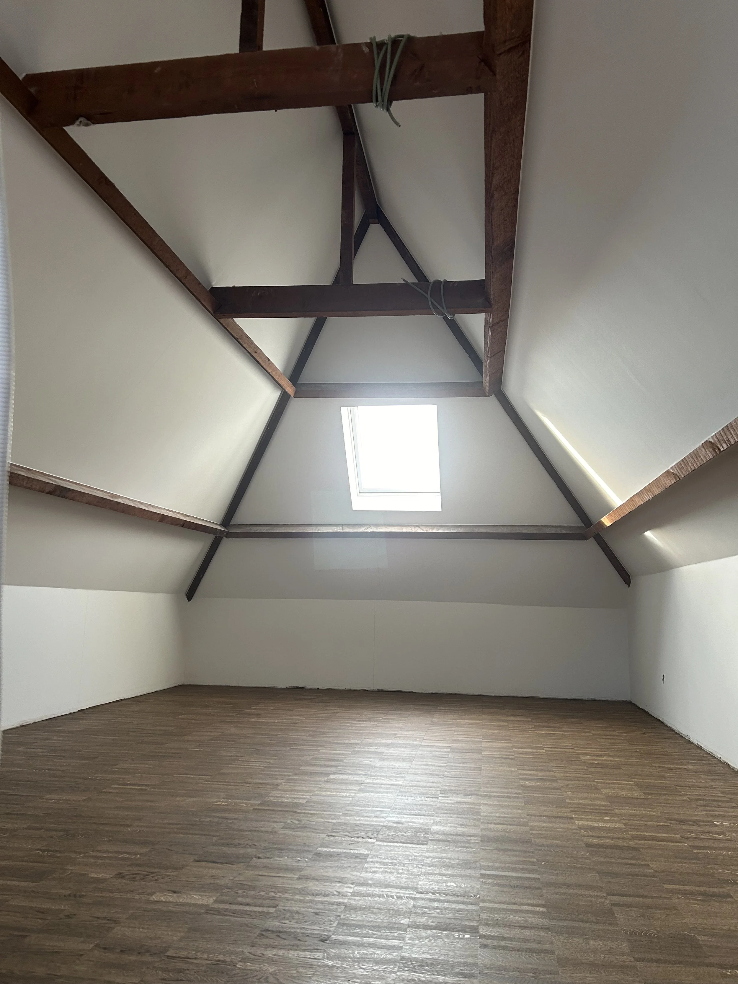 Afgewerkte zolderruimte met gyprocwanden en originele houten dakbalken, zolderinrichting door Sorgeloose in Brugge