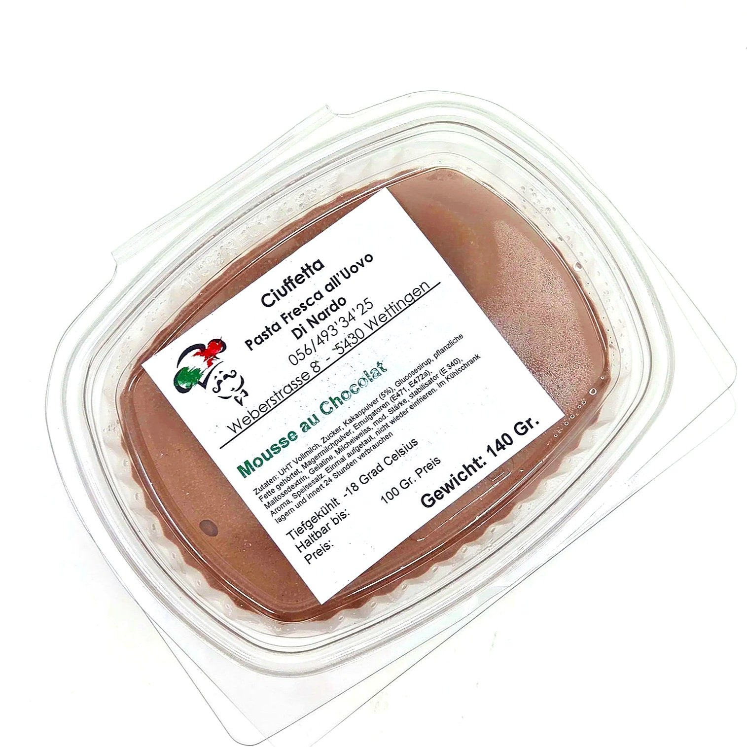 Ein transparentes Kunststoffbehälter mit brauner Schokoladencreme, Etikett mit Produktinformationen in deutscher Sprache, inklusive Name, Zutaten, Gewicht (140 Gramm) und Lagerhinweis.